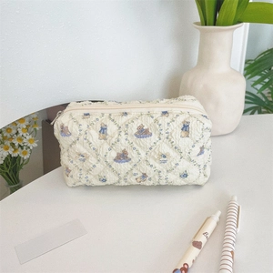 Dettaglio della borsa cosmetica trapuntata beige con motivi floreali blu e coniglio vintage