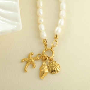 Dettaglio collana di perle d'acqua dolce con ciondoli stella marina e conchiglia dorati