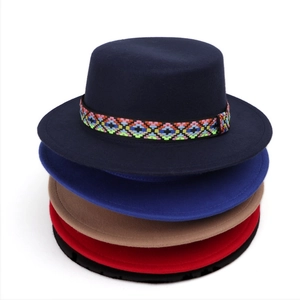 Detailed stack of colorful wool felt flat top hats with ethnic embroidered bands