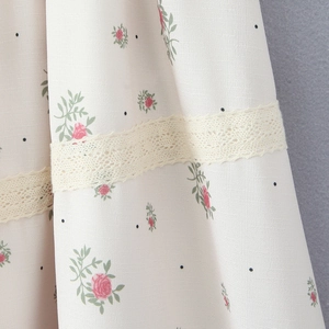 Floral print dress fabric with pink flowers and delicate beige lace detail close-up