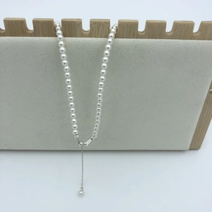 Detail of white round pearls necklace with S925 silver clasp on velvet jewelry display