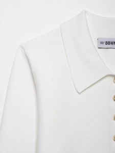 Close-up of white knitted cardigan with gold metal buttons and classic collar detail
