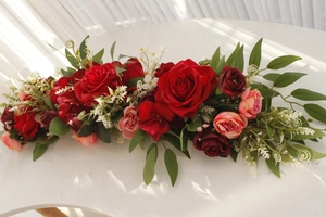 Detail of red and pink silk rose floral runner for wedding chairs and table decoration