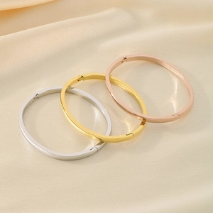 Three minimalist oval bangles in silver gold and rose gold on a beige silk background