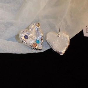 Close-up of heart earrings with ruffled metal texture and multi-colored gemstones
