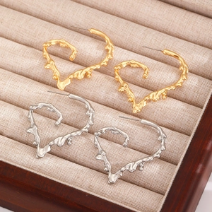 Macro detail of gold and silver heart hoop earrings with irregular liquid metal texture