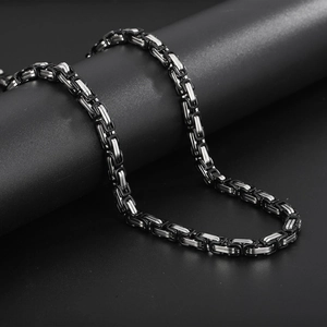 Close-up of black and silver Byzantine king chain necklace on a black cylindrical stand