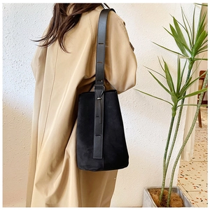 Detail of wide leather strap and suede bucket bag on model with minimalist autumn style