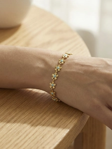 Close-up of gold flower chain bracelet with light blue enamel petals on a wooden surface