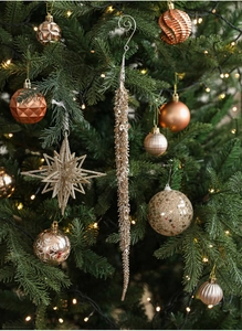 Detail of glitter star and baubles on Christmas tree with warm holiday lighting