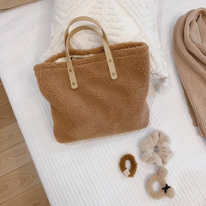 Brown fleece tote bag with beige leather handles on white quilted background
