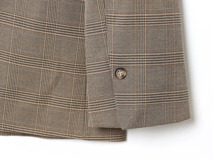 Gros plan du poignet d'un blazer à carreaux marron avec bouton marbré et texture fine