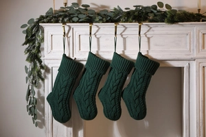 Deep green knit Christmas stockings hung on a fireplace for holiday decoration