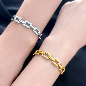 Close-up of gold and silver thick square link chain bracelets with polished metallic finish