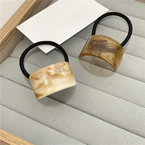 Detail of marble pattern acrylic hair ties on a gray velvet tray with elegant aesthetics