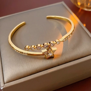 Close-up of gold-plated star bracelet with cubic zirconia on a gray jewelry box