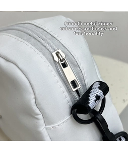Detailed shot of polished silver metal zipper head on white nylon crossbody bag