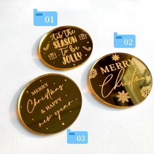 Macro detail of three gold mirror acrylic Christmas cake toppers with festive engravings