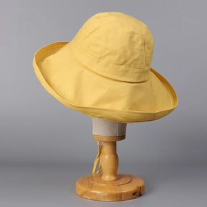 Detail of yellow cotton linen sun hat featuring a wide brim and adjustable chin strap