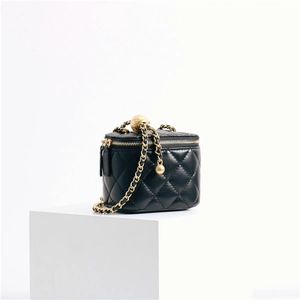 Macro detail of black quilted lambskin mini vanity bag with gold chain and ball buckle