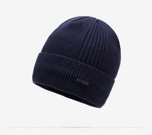 Detail of navy blue ribbed knit beanie with small black brand logo tag on the side