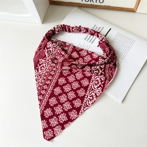 Detailed flat lay of a red paisley cotton headscarf with elastic band on a magazine