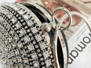 Macro detail of silver rhinestone evening bag with polished metal clasp and crystal texture