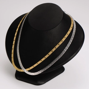 Flat herringbone snake chain necklace in gold and silver finish on a black display bust