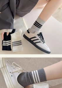 Detailed knit texture of athletic crew socks with three stripes in gray and white