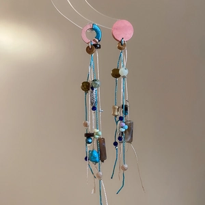 Detail of ethnic tassel earrings featuring turquoise beads and handmade silk threads