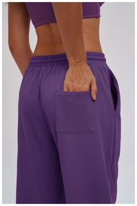 Detail view of purple joggers featuring an elastic waistband and back pocket design