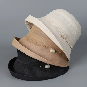 Detailed texture of woven straw sun hats featuring pearl bands and rhinestone buckles
