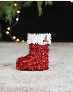Close-up of red glitter Christmas boot decoration with white trim and green holly leaves