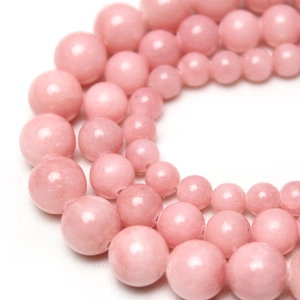 Perles rondes en pierre naturelle rose pour la création de bijoux sur tissu blanc