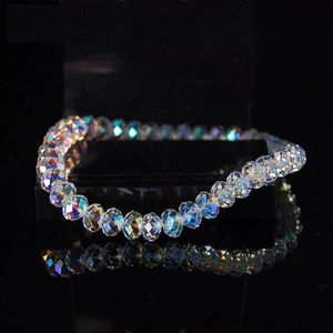 Detailed view of iridescent crystal beaded bracelet with rainbow refraction on black stand