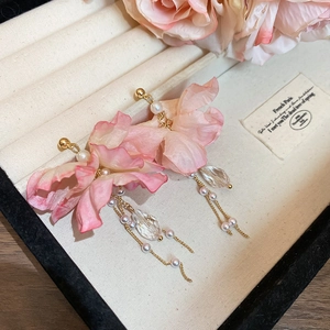 Macro detail of pink fabric flower earrings with pearl tassels and crystal charms