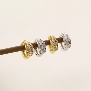 Détail de boucles d'oreilles en forme de feuilles avec zircons en doré et argenté