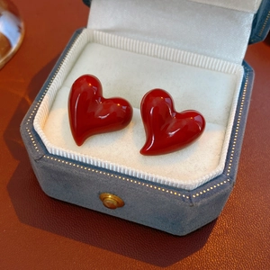 Macro shot of red heart stud earrings with gold plating in a vintage blue jewelry box
