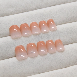 Glossy peach gradient press-on nails displayed on a velvet tray with a high-shine finish