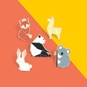 Macro detail of geometric origami animal enamel pins featuring fox, panda, and rabbit designs