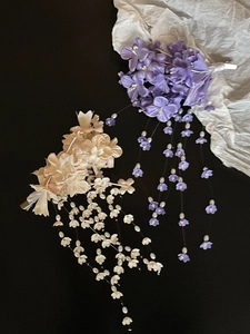 Detail of lily of the valley hair clips with silk petals and pearl tassels on black background