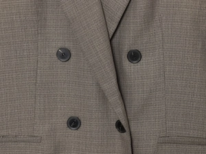 Detail of dark brown double-breasted blazer showing premium twill fabric and buttons