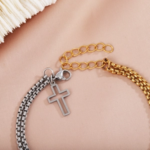Detail of gold and silver layered chain bracelet with cross pendant and lobster clasp