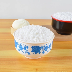 Realistic artificial white rice in a blue and white floral ceramic bowl prop