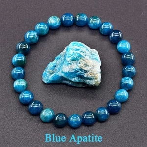 Macro shot of polished Blue Apatite round beads with a raw natural stone centerpiece