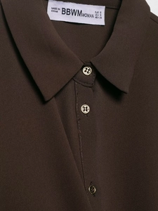 Detailed view of dark brown creped shirt collar with gold metal button and woven texture