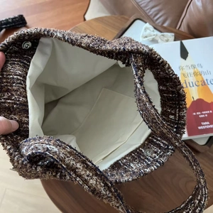 Detail view of tweed tote bag showing canvas lining, interior pocket and magnetic closure