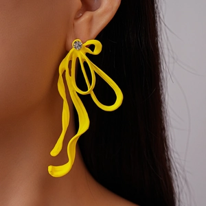 Close-up of yellow pleated bow earrings with a small diamond accent on model ear