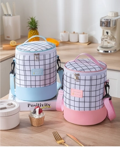 Detail of blue and pink cylindrical lunch bags with grid pattern and adjustable straps