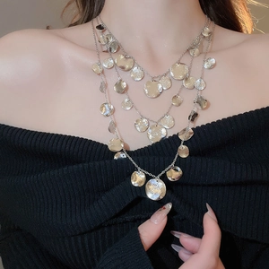 Close-up of triple-layered silver necklace with hammered metal disc pendants on a model